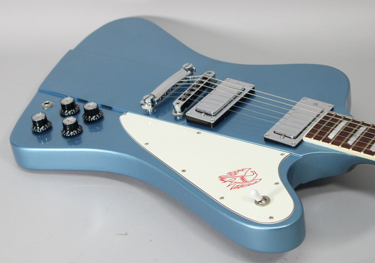 Pelham Blue Firebird body, angled from the lower bout, showing the white pickguard with red bird graphic, chrome hardware, and four black knobs.