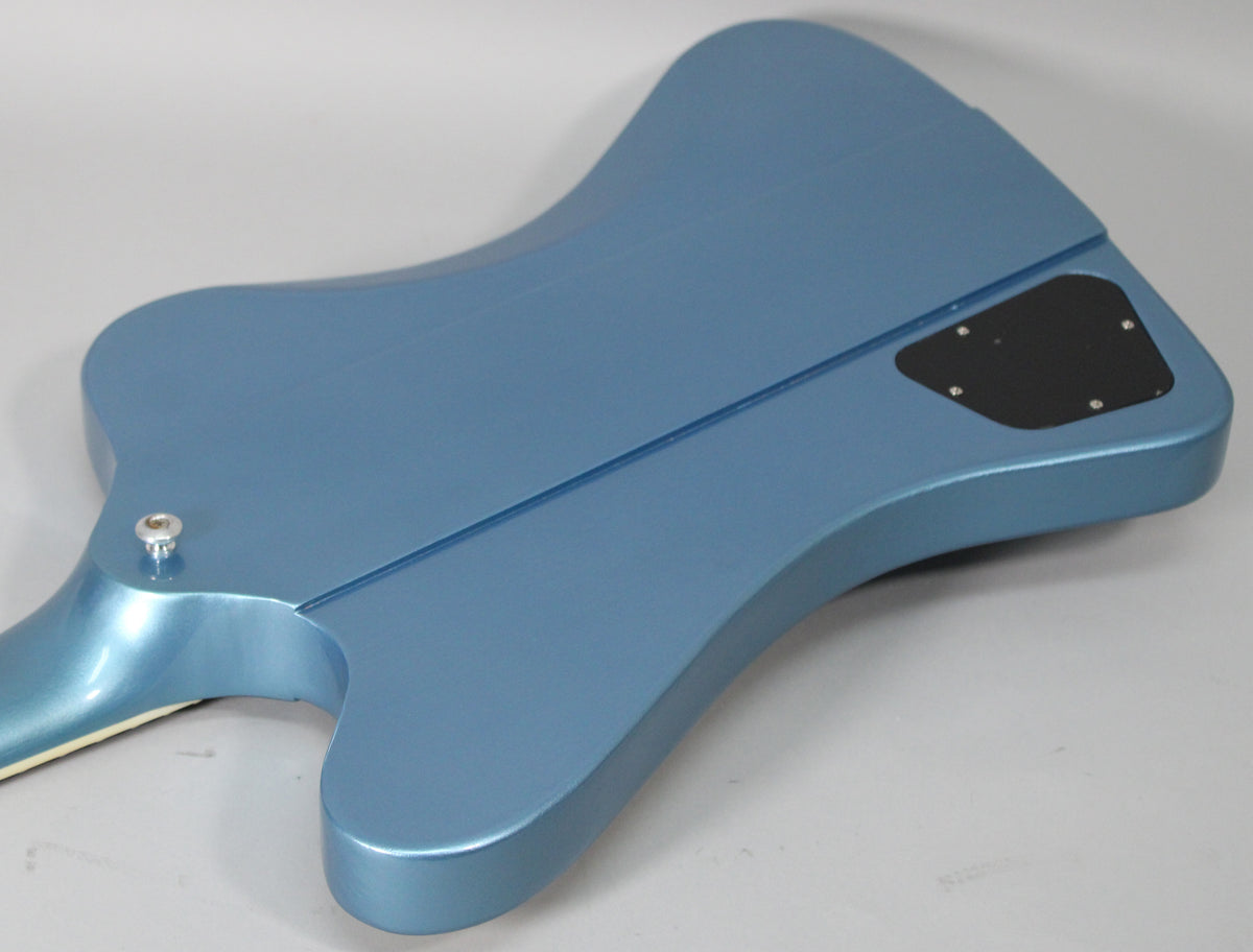 The back of a Pelham Blue Firebird guitar, showing the neck joint, strap button, and black control cavity cover.