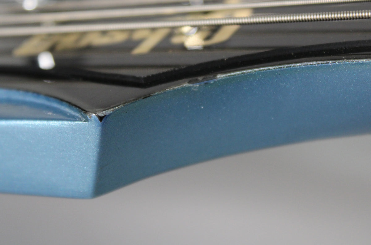 Close-up of the Pelham Blue headstock's edge, showing a small chip in the finish where it meets the black headstock face.