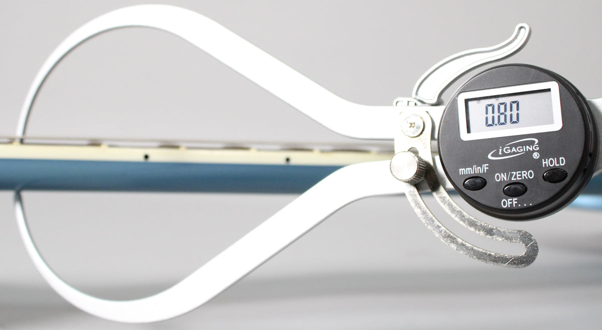 A digital caliper measures the Pelham Blue neck, showing 0.80 on its screen, with light wear on the caliper's lower arm.