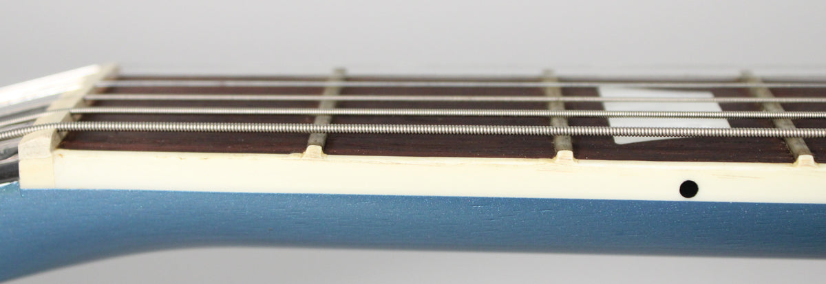 Close-up of the guitar's neck from the side, showing the Pelham Blue finish, cream binding, dark fretboard, and a black side dot.