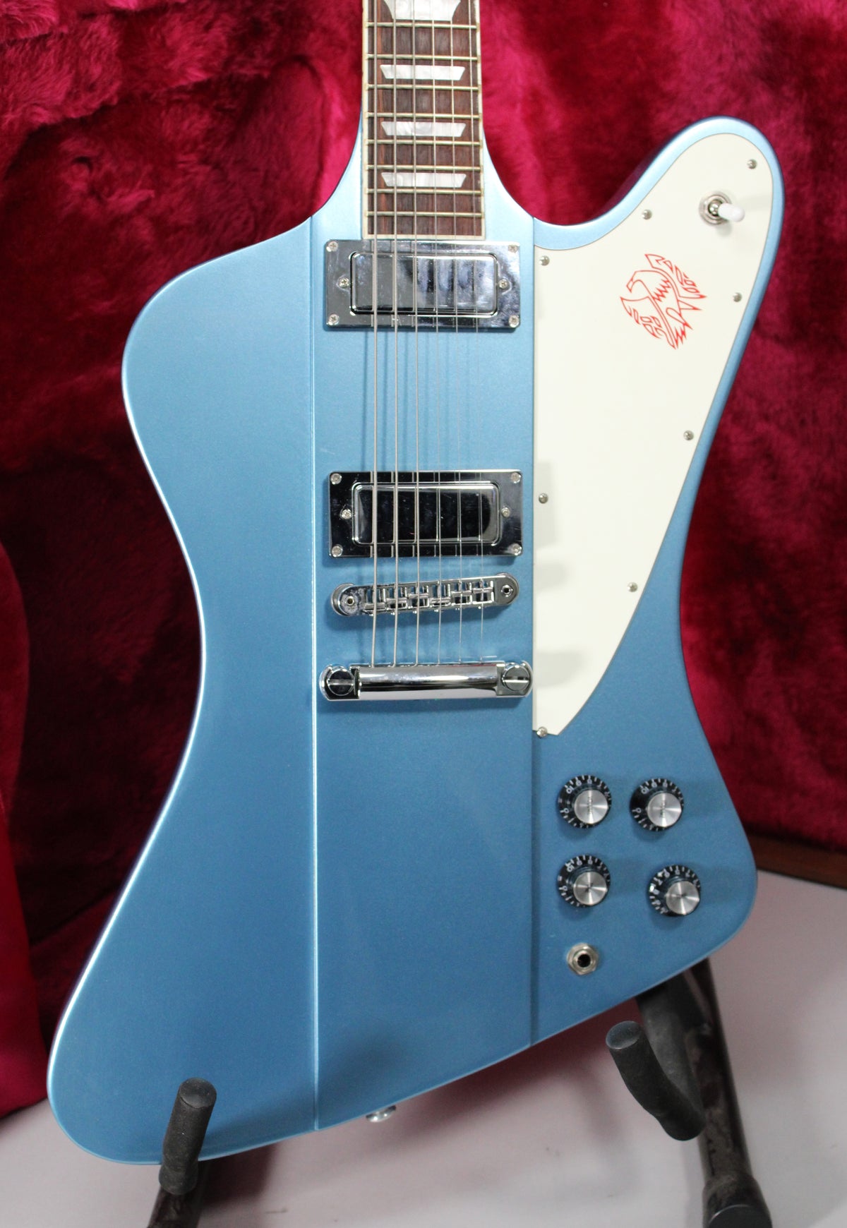 Full-frame view of a Pelham Blue Firebird, showing the body, neck, two humbuckers, white pickguard with red bird graphic, and four chrome knobs.