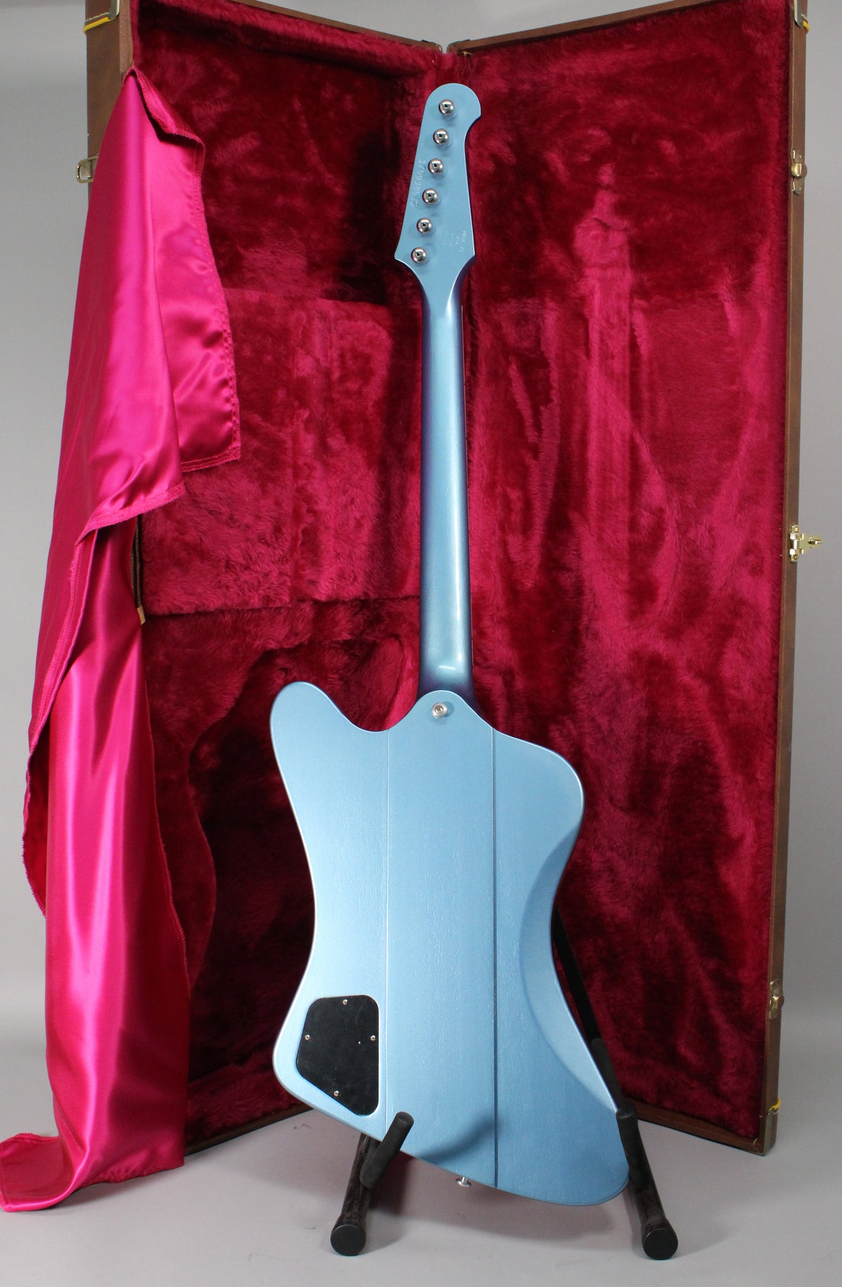 The Pelham Blue Firebird's back, neck, and headstock are visible, with a black control cavity cover and six tuners.