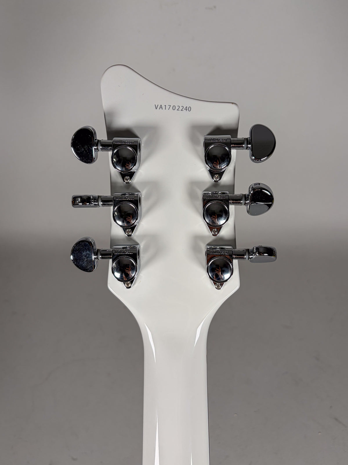 The back of the white headstock and top of the neck, showing six chrome tuners with kidney-bean shaped buttons.