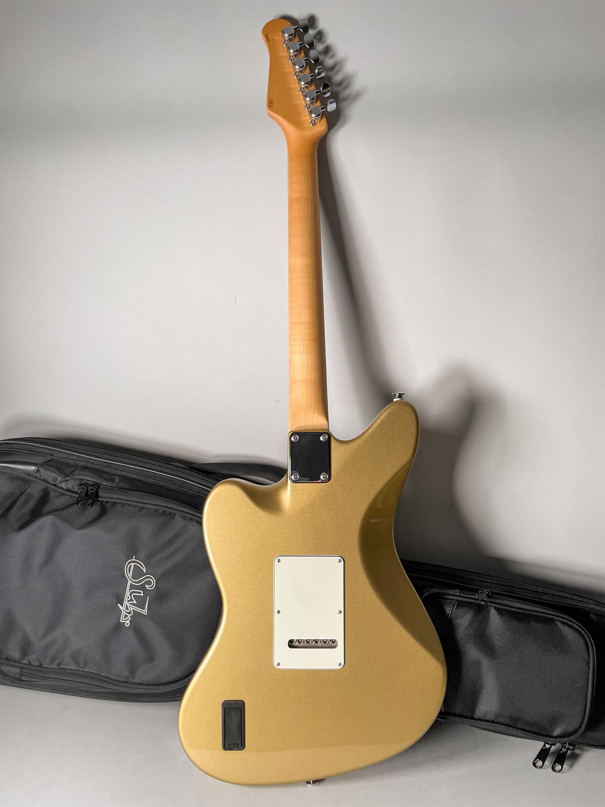The back of a gold metallic guitar with a light maple neck, chrome tuners, and a white backplate.