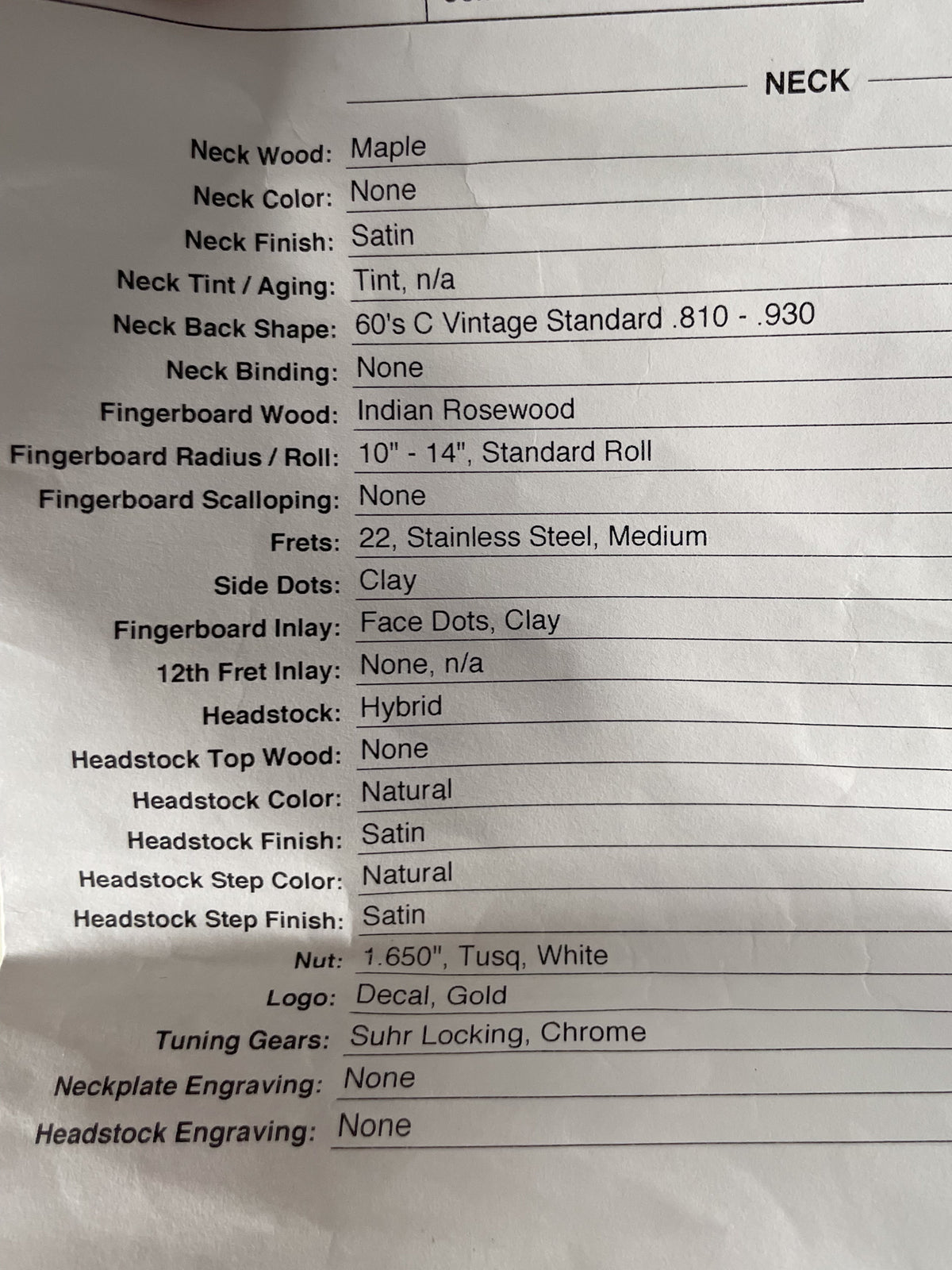 A close-up of a white paper spec sheet for the guitar, showing details like neck wood, fingerboard wood, and headstock finish.