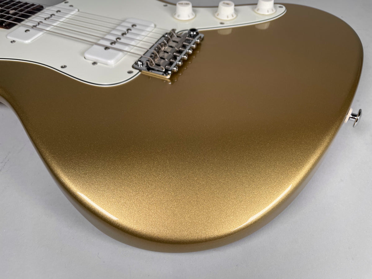Close-up of a gold sparkle guitar body with a white pickguard, two white S90 pickups, a chrome bridge, and three white control knobs.