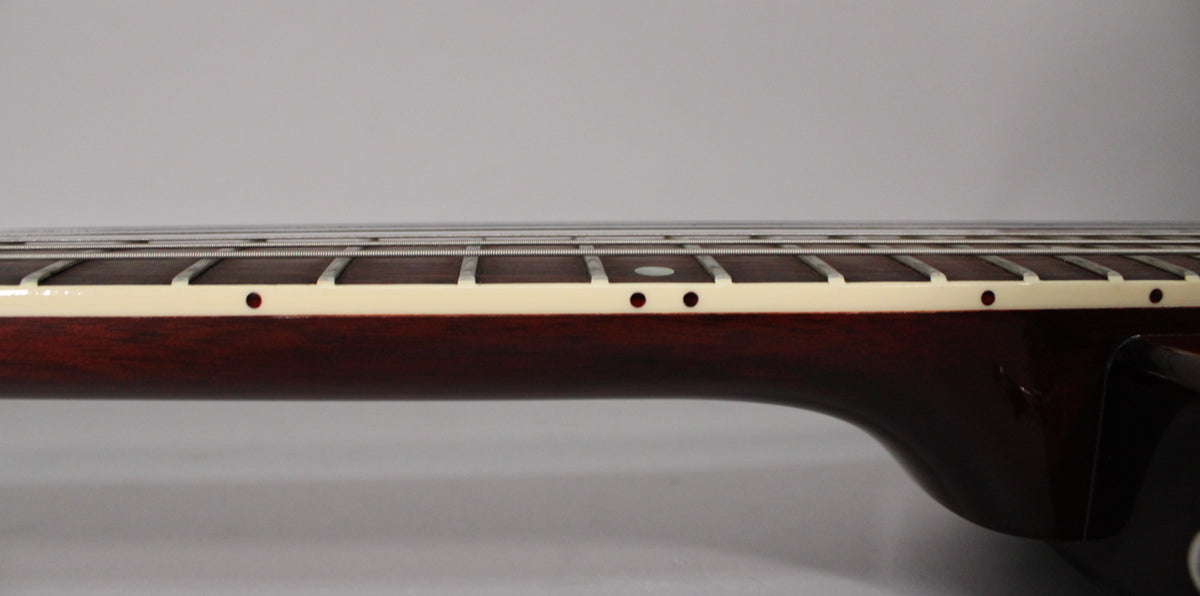 The dark cherry neck and fretboard are shown from the side, revealing cream binding and small black dot inlays.