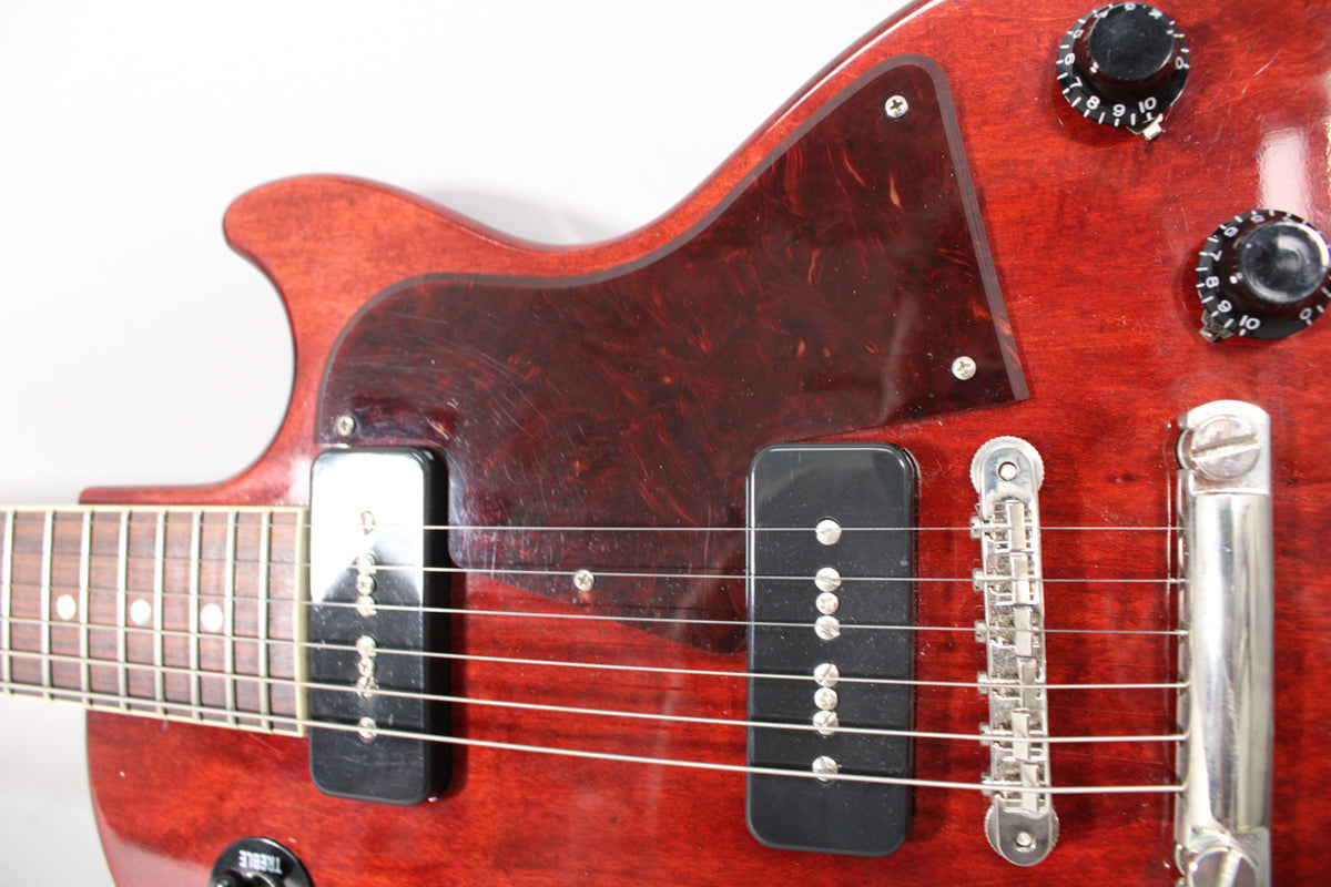 Close-up of the dark cherry body, showing two black P90 pickups, a tortoiseshell pickguard, and two black control knobs.