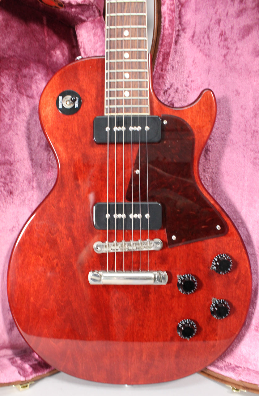 The dark cherry Les Paul Special is angled in its pink-lined case, showing its two P90 pickups, tortoise pickguard, and four black knobs.