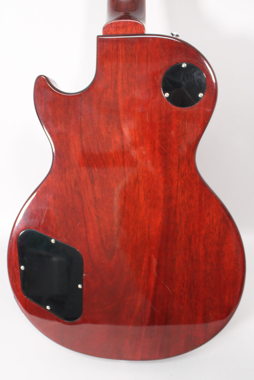 The guitar's dark cherry back shows visible wood grain, two black control cavity covers, and light surface scratches.