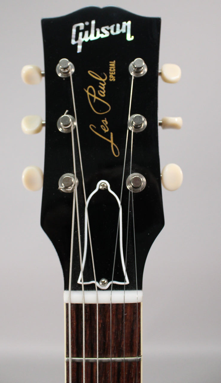Close-up of a glossy black headstock with six cream-button tuners, a white bell-shaped truss rod cover, and a dark rosewood fretboard.
