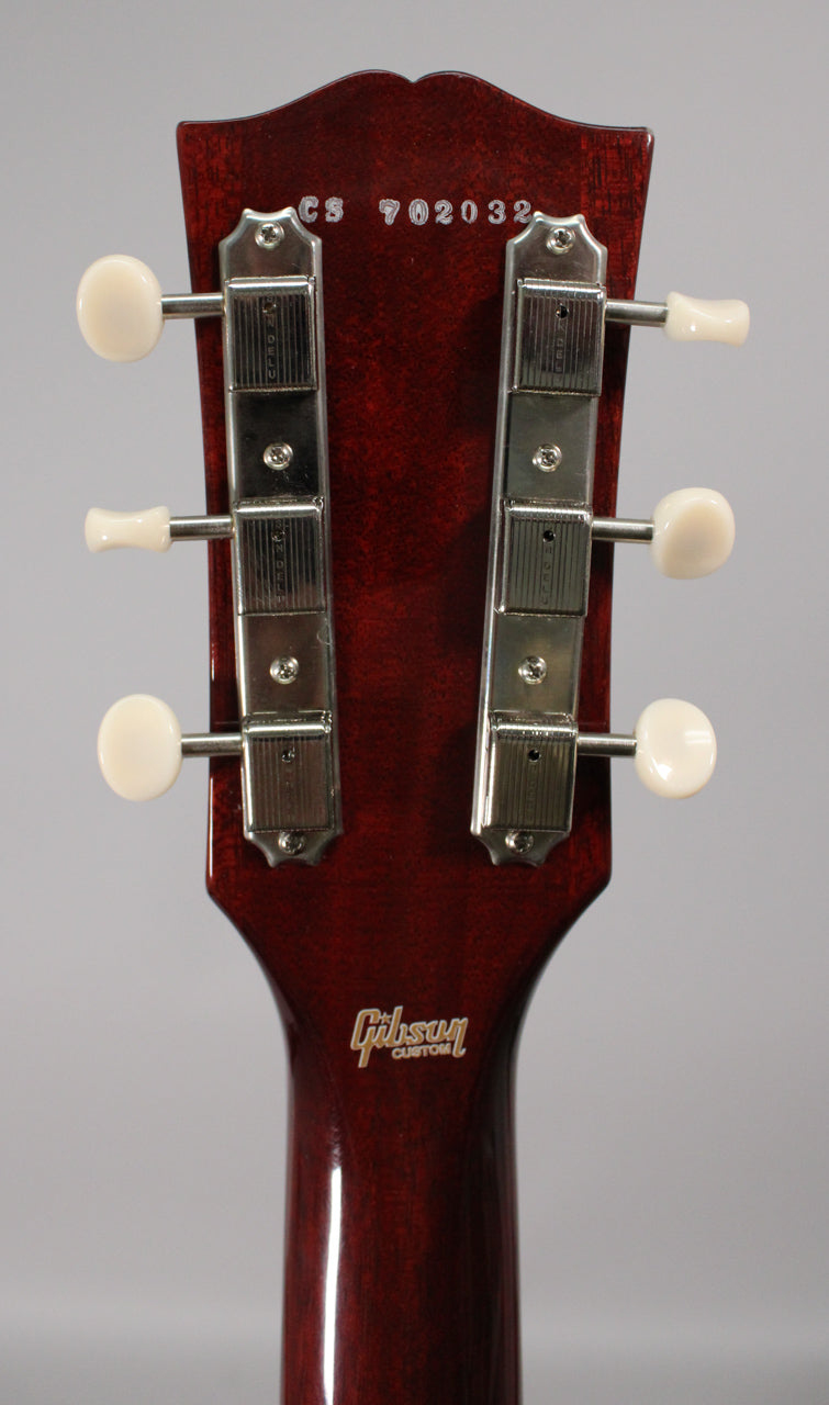 The back of a dark cherry headstock with a glossy finish, showing six cream-colored tuning pegs and chrome tuners.