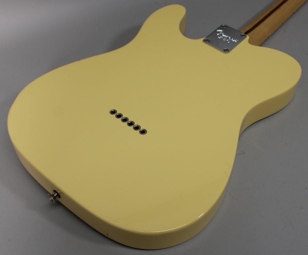 The back of a vintage white Telecaster body, showing six string-through-body ferrules, a chrome neck plate, and strap button.