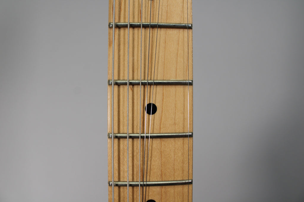 Close-up of the Telecaster's maple fretboard, showing five frets, six strings, and black dot inlays on the 7th and 9th frets.