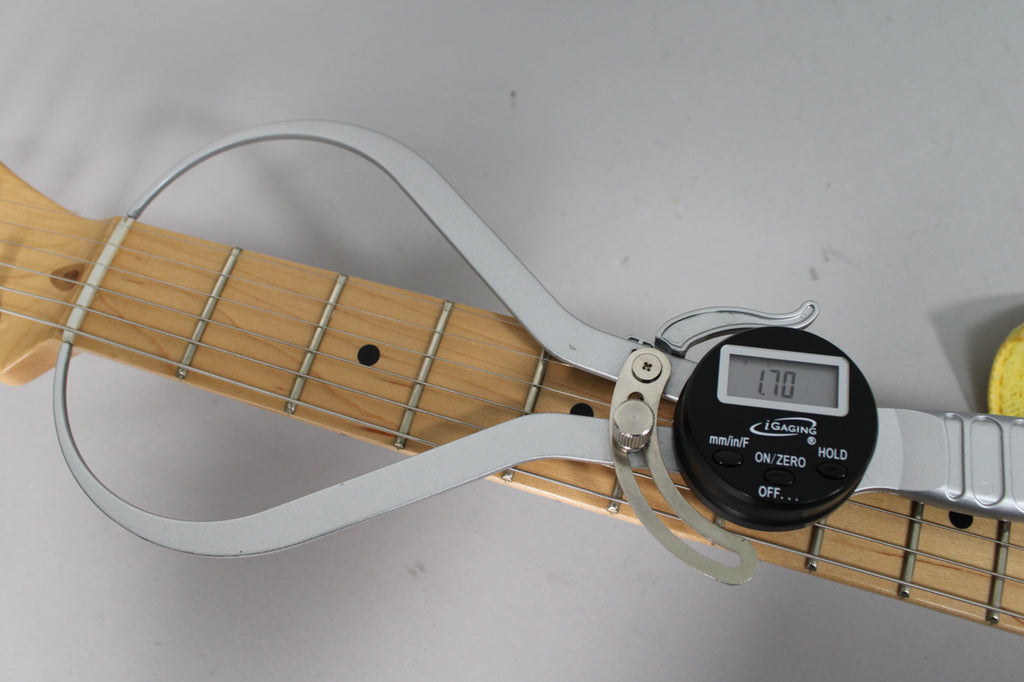A digital fret height gauge measures the maple fretboard and frets of the guitar neck, displaying "1.70".