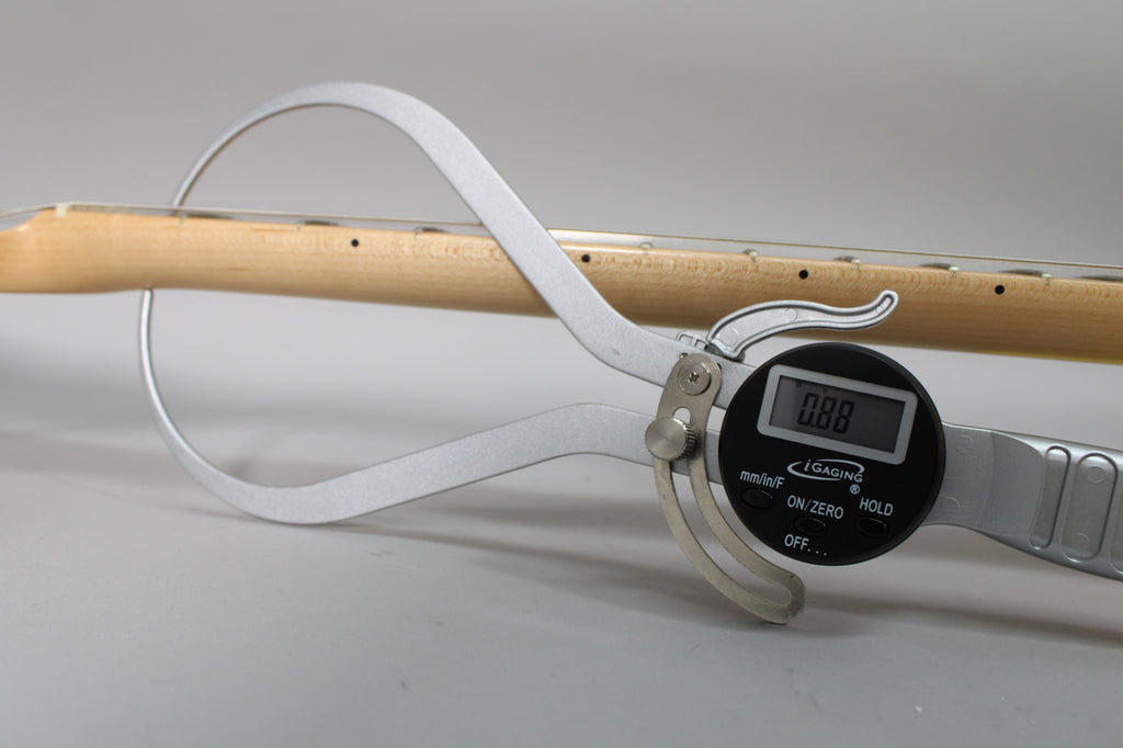A digital caliper measures the natural wood neck of the guitar, showing a reading of 0.88.
