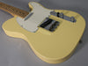 A vintage white Telecaster, angled from the neck, showing the body, white pickguard, chrome bridge, and control plate with two knobs.