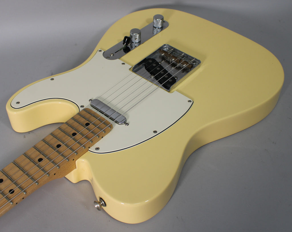 Vintage white Telecaster body, angled from the lower bout, showing a maple fretboard, white pickguard, and chrome hardware.