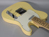 The vintage white Telecaster body is angled, showing the chrome bridge, control plate with two knobs, and a maple fretboard.