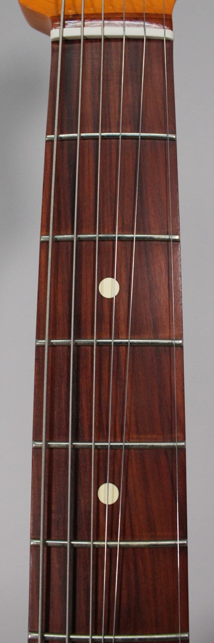 Close-up of the dark wood fretboard with six strings, silver frets, and two cream dot inlays at the 7th and 9th frets.