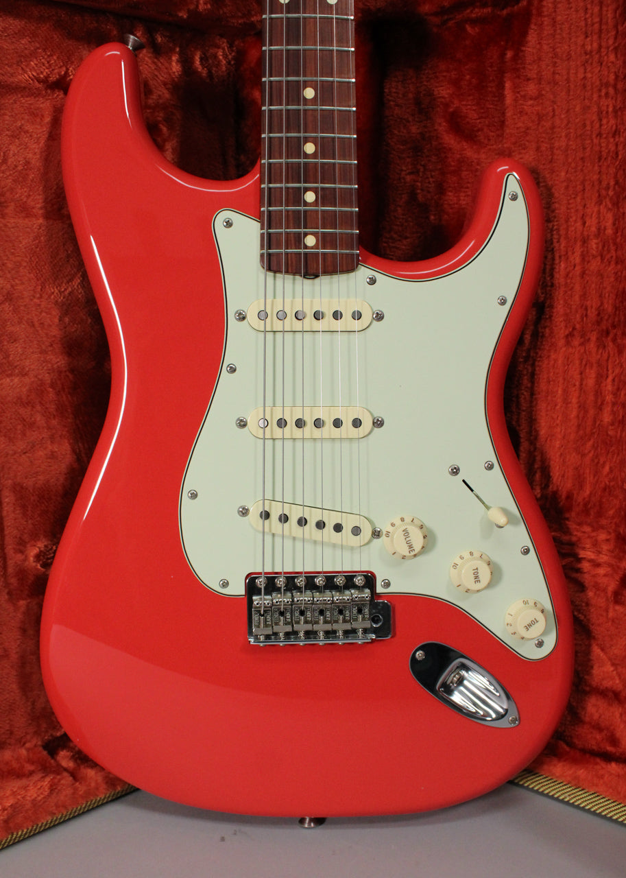 Full front view of a glossy red Stratocaster with a mint green pickguard, three cream single-coil pickups, and chrome hardware.