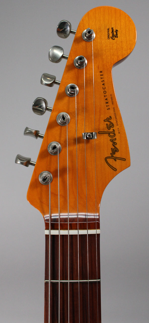 Close-up of the guitar's headstock, showing six chrome tuners, a string tree, and the dark Pau Ferro fingerboard with white nut.