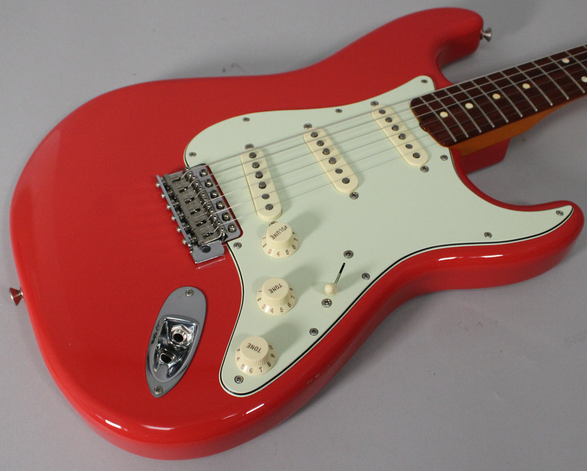 The Fiesta Red Stratocaster body is angled, showing its glossy finish, white pickguard, three cream pickups, and chrome hardware.