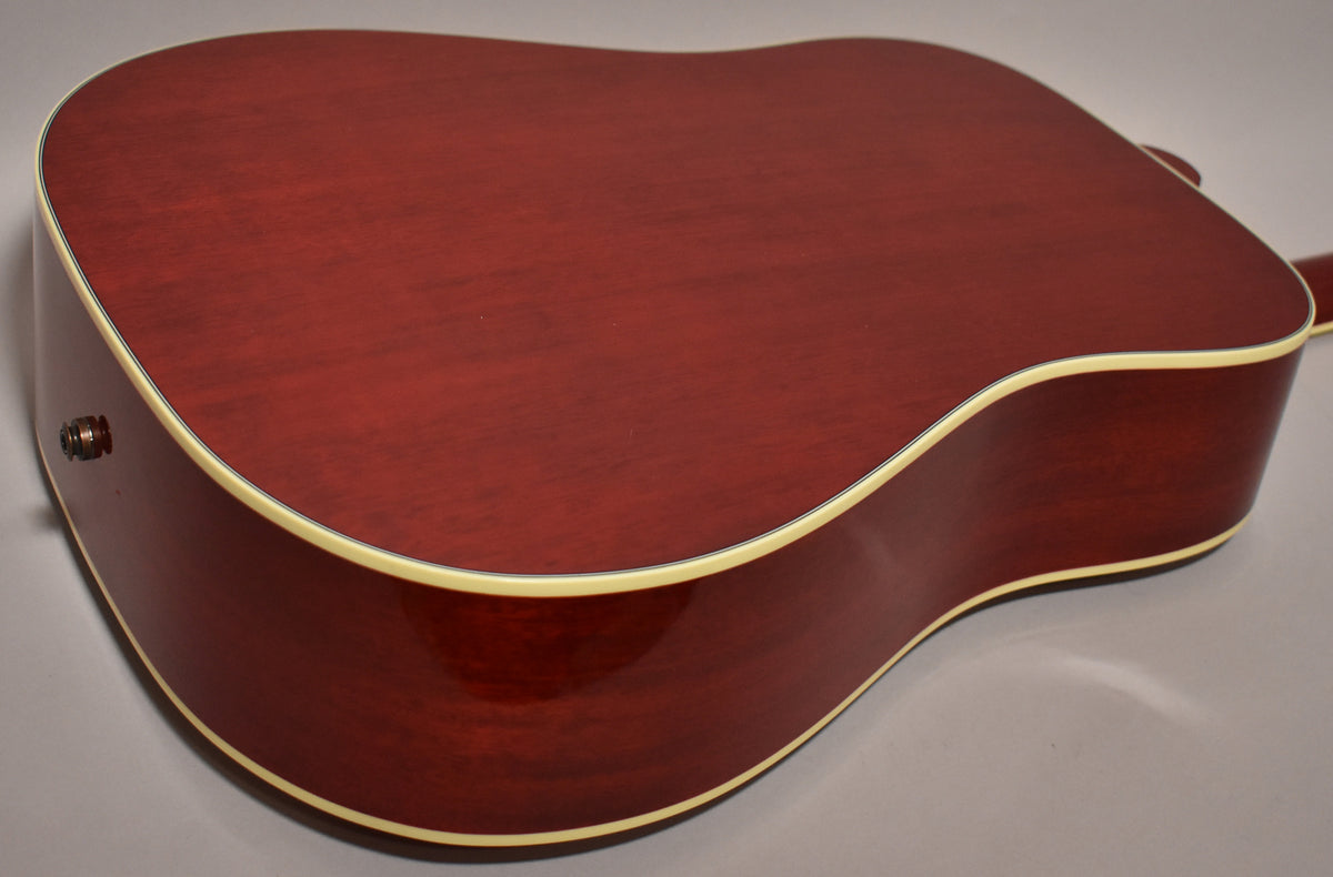 The guitar's cherry sunburst back and side are visible, with cream binding and a chrome endpin jack on the lower bout.