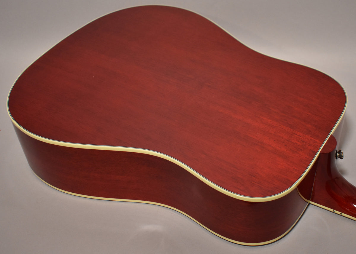 The back of the cherry sunburst acoustic guitar, showing the deep red wood grain and cream binding, with a hint of the neck.