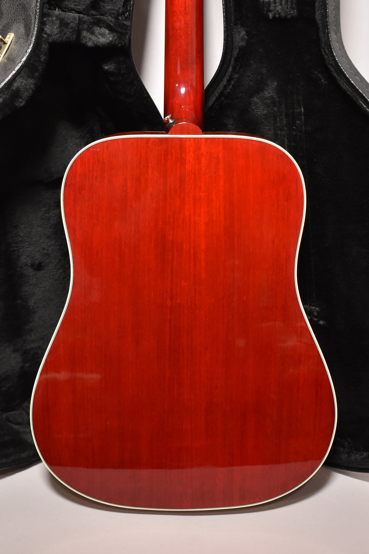 Full rear view of a cherry sunburst acoustic guitar, showing the glossy red body with visible wood grain and a white binding.
