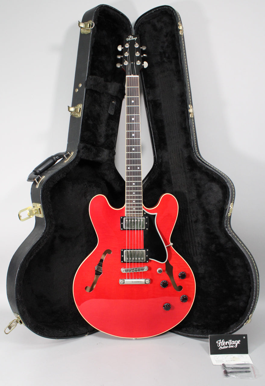 Full-length view of a glossy red semi-hollow guitar with f-holes, black pickguard, two humbuckers, and four black control knobs, in its open black hard case.
