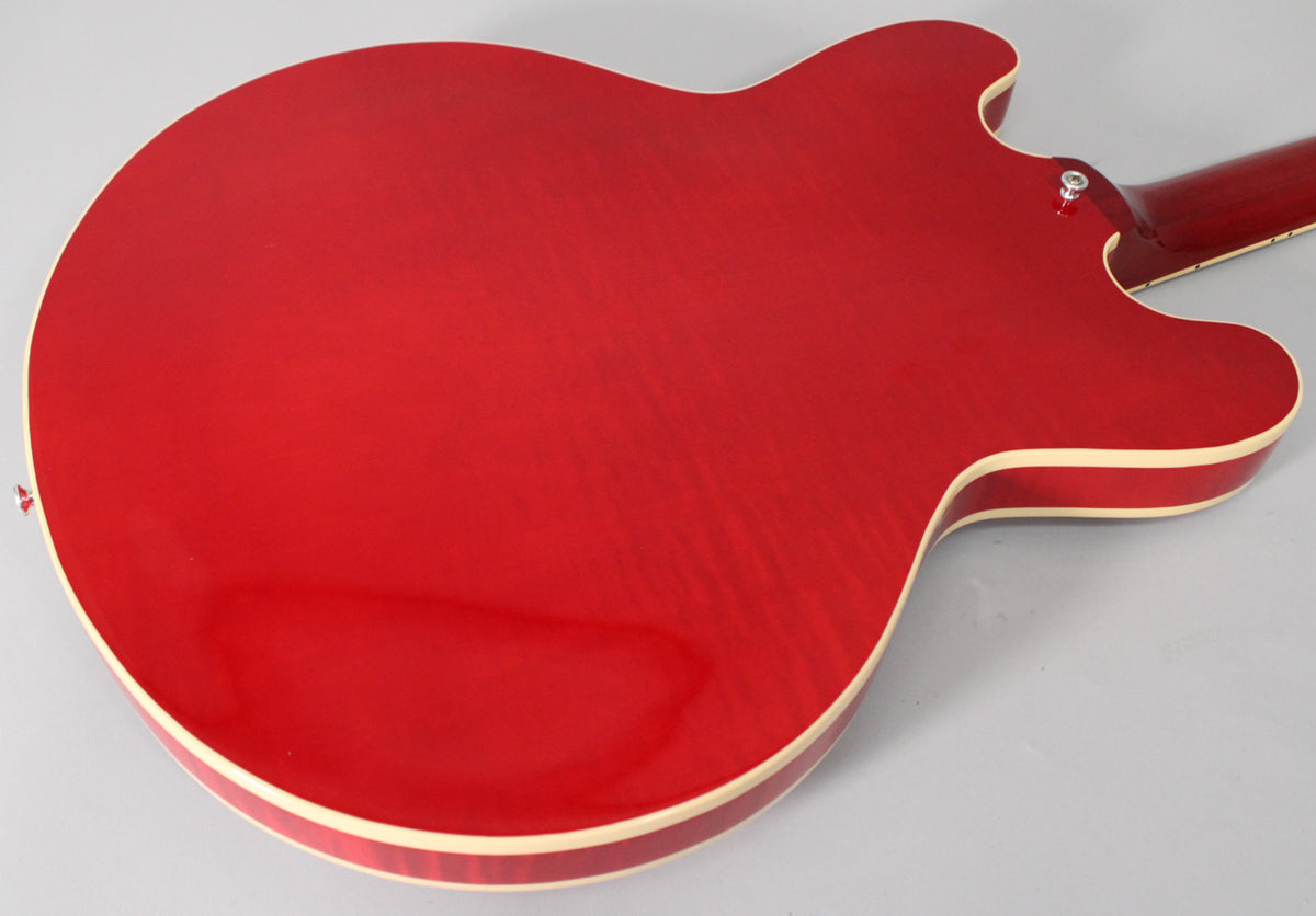 The back of a trans red semi-hollow guitar, showing the flame maple grain through the glossy finish and cream binding.