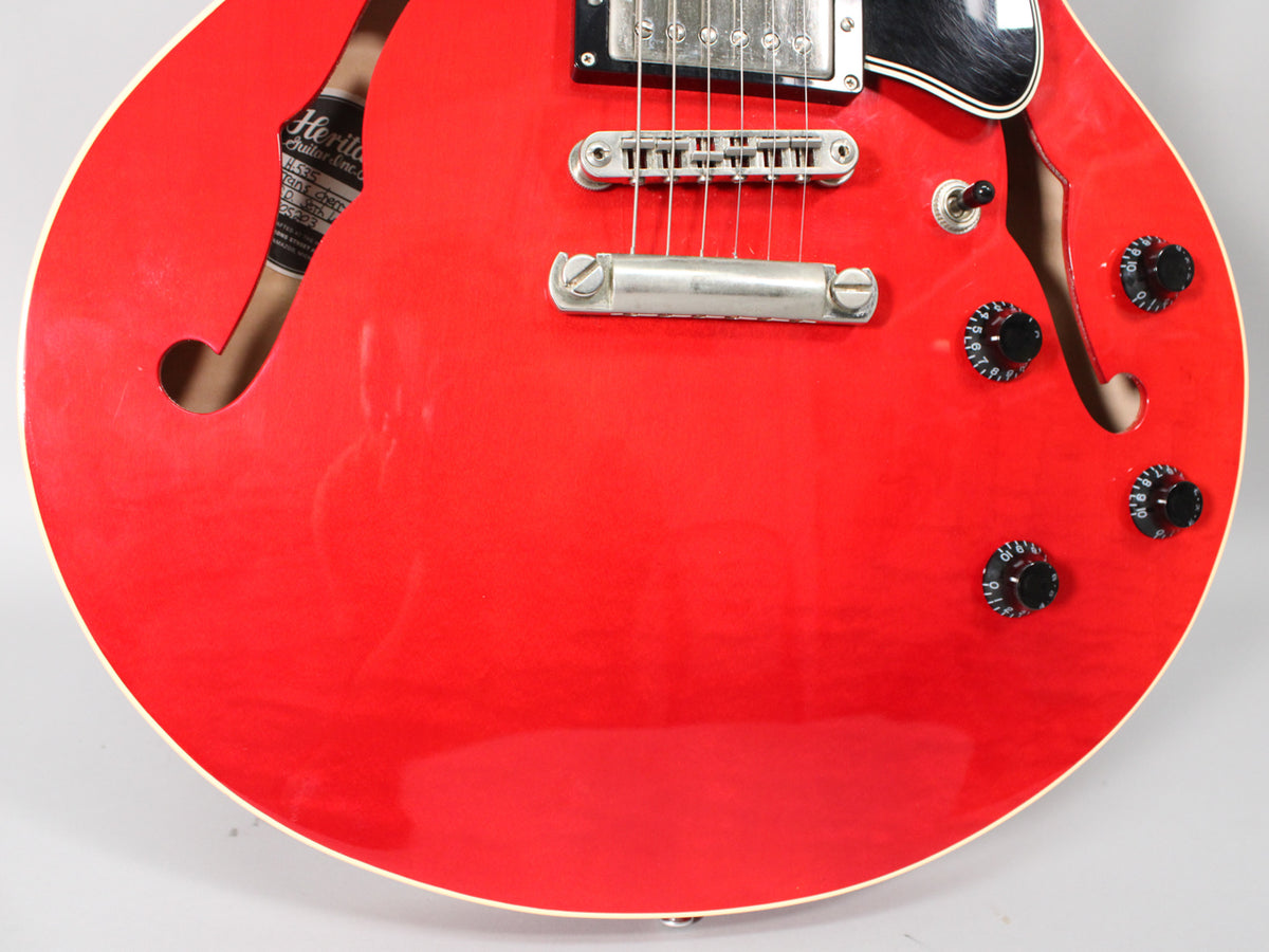 Close-up of the glossy trans red semi-hollow body, showing the f-holes, four black control knobs, and chrome bridge and tailpiece.