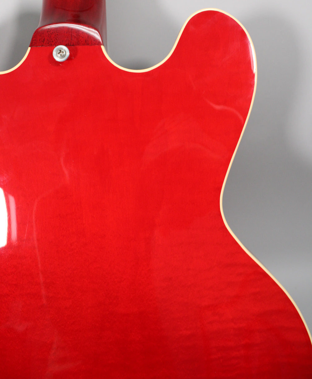 The back of the guitar's trans red body, showing the neck joint and cream binding along the upper bout.