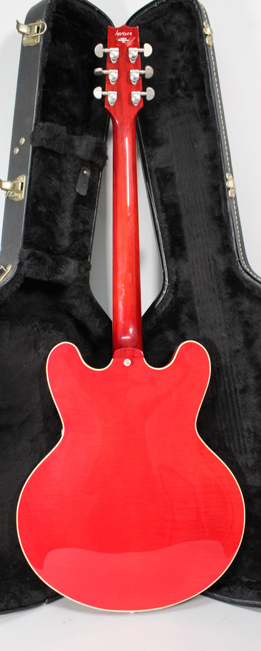 The back of a glossy trans red semi-hollow guitar with cream binding, showing the neck and headstock with six chrome tuners.