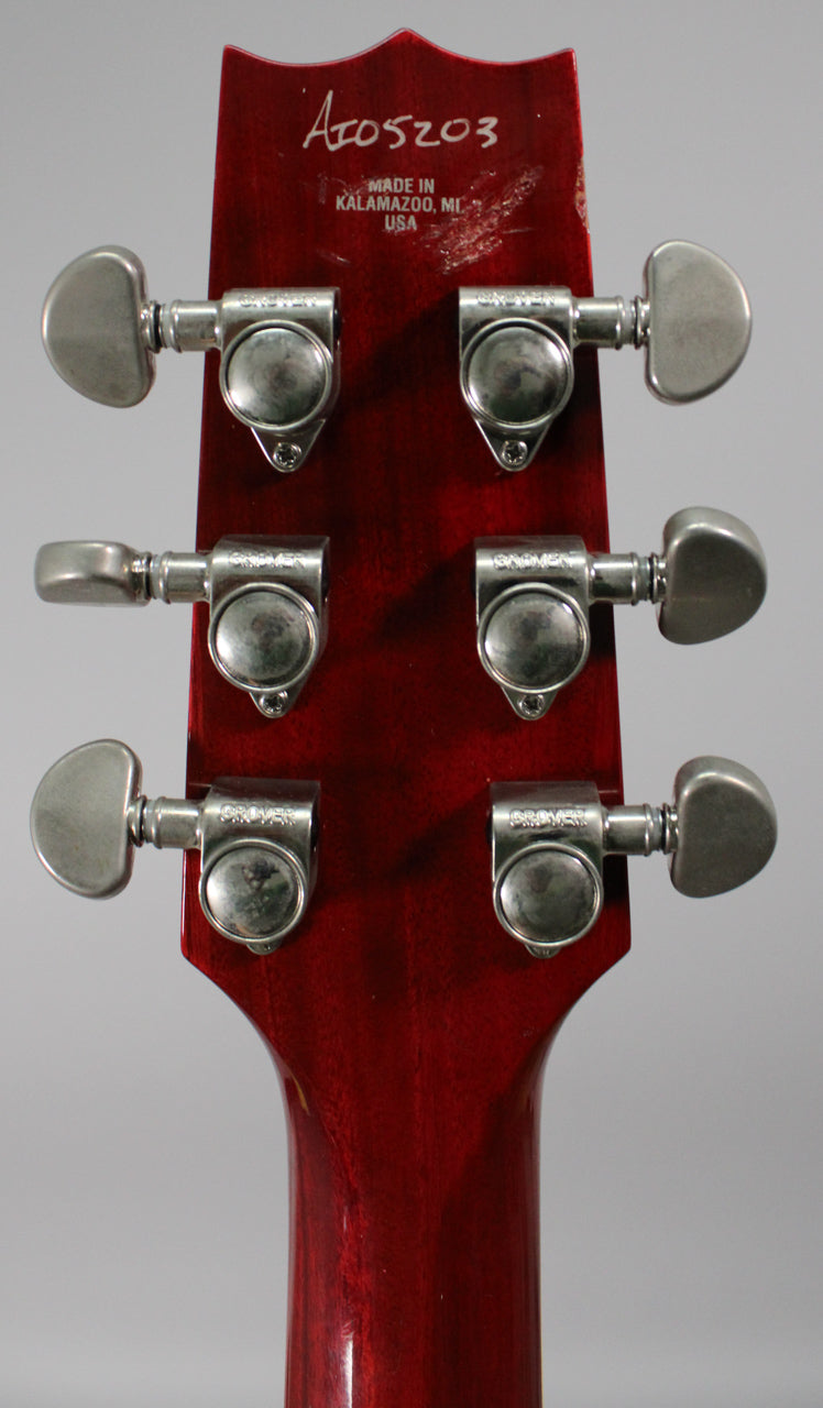 The back of the guitar's headstock and neck in trans red, showing six Grover tuners with some wear and light scratches.