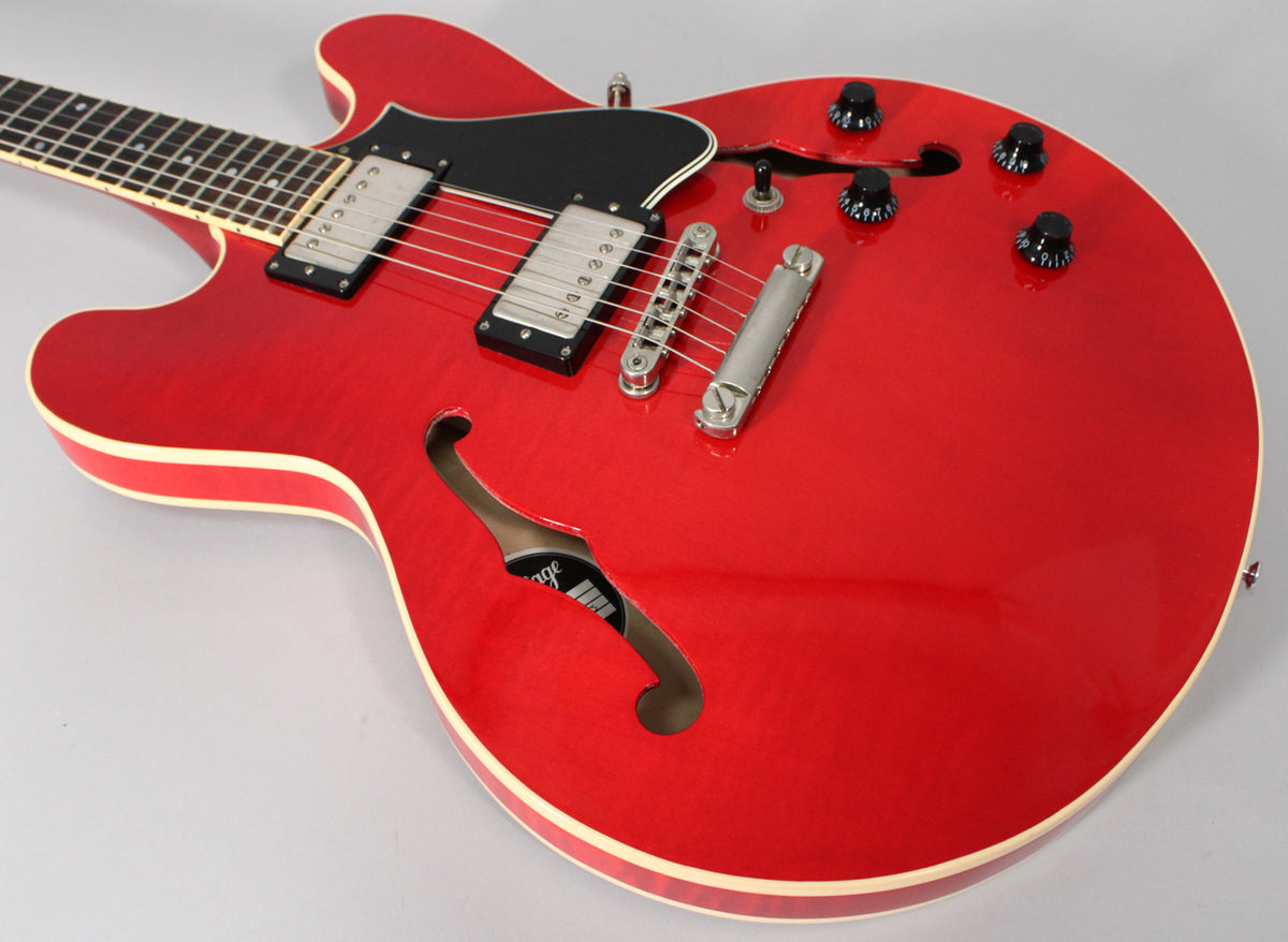 Upper body of a trans red semi-hollow guitar, showing two humbuckers, black pickguard, f-hole, and four black control knobs.