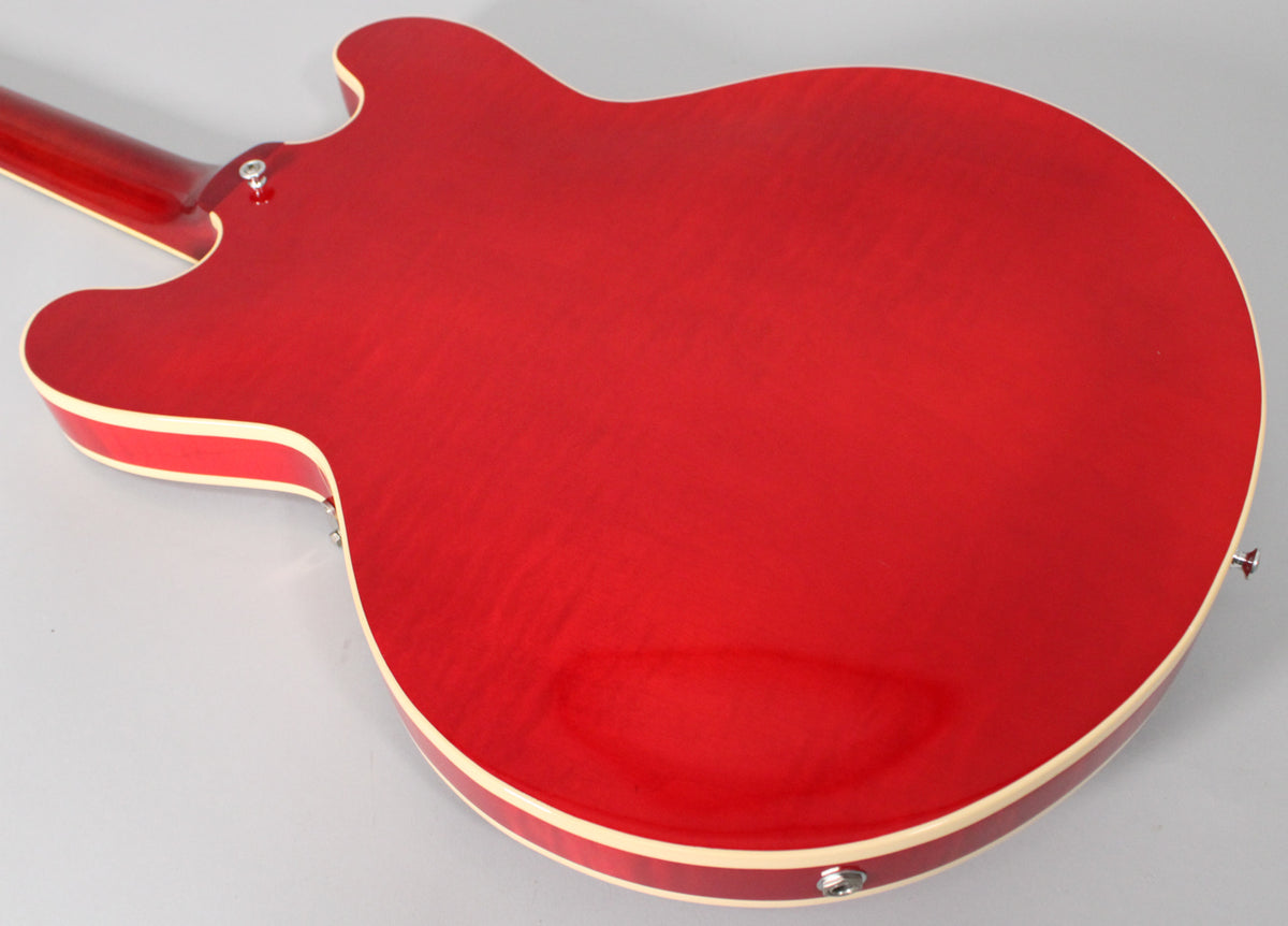 The back of a trans red semi-hollow guitar with cream binding, showing the neck joint and output jack.