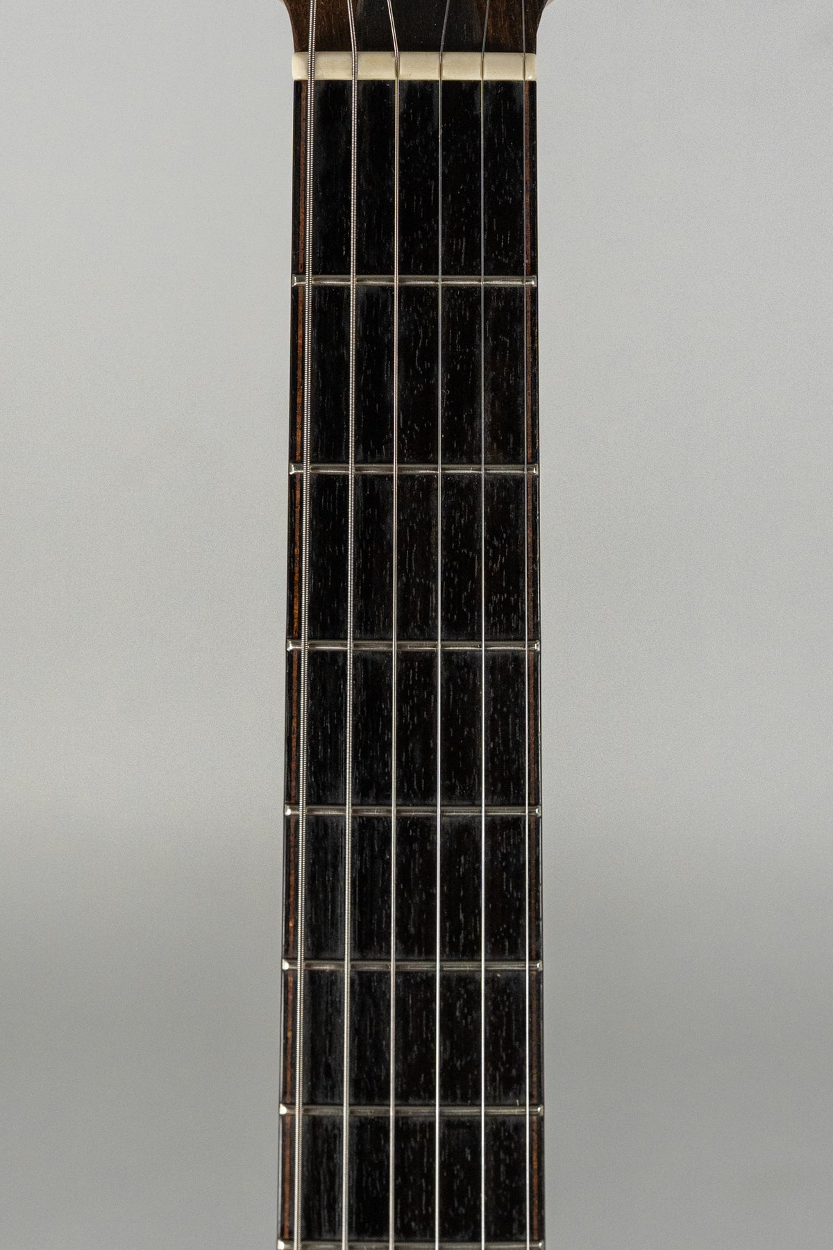 A close-up of the guitar's dark fretboard, showing the first 10 frets and the white nut at the top.