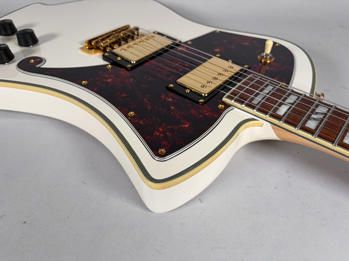 Upper body of a white electric guitar with a tortoiseshell pickguard, gold hardware, and block inlays on the fretboard.