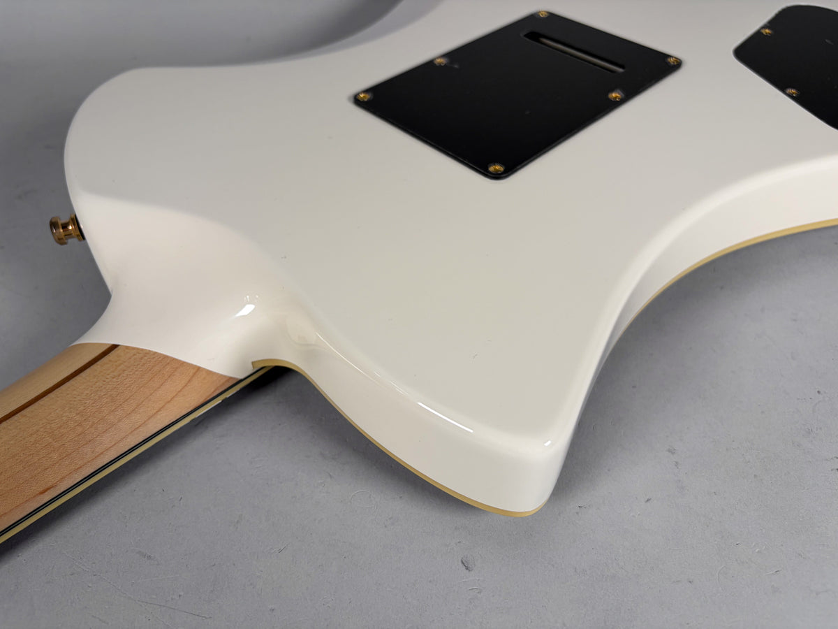 The back of a white electric guitar, showing the neck joint, two black control plates, and a gold strap button.