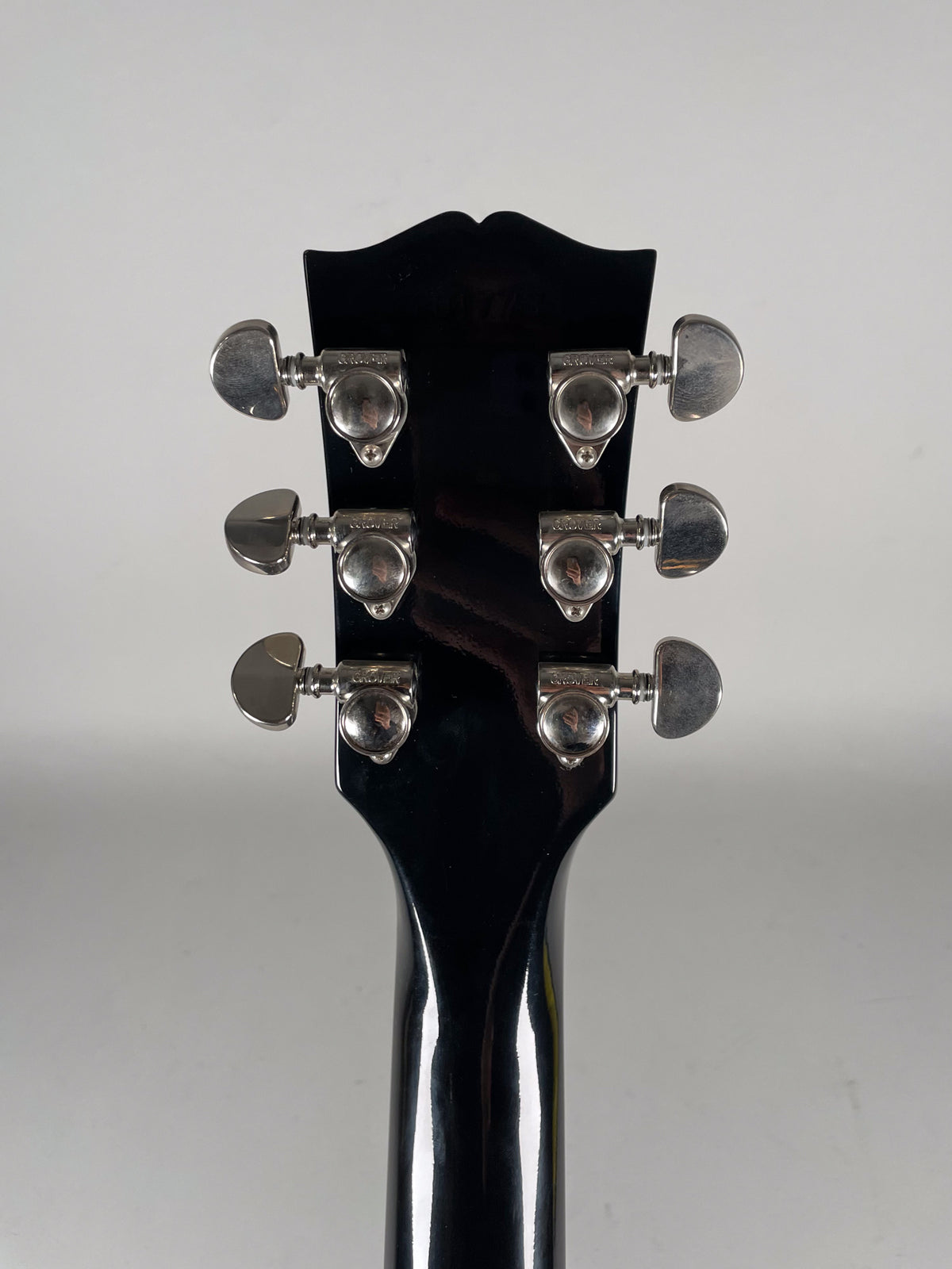 Rear view of the glossy black headstock and neck, showing six chrome tuners with minor tarnishing.