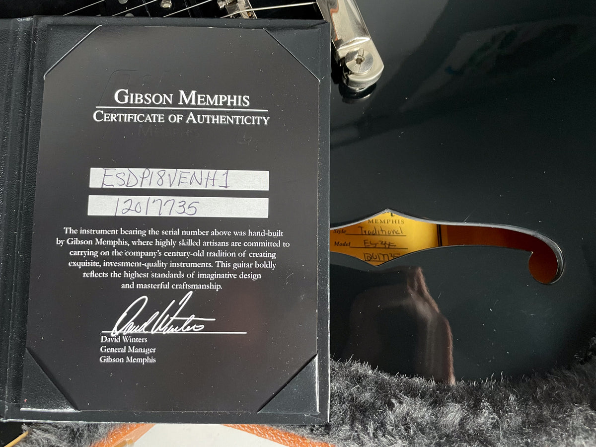 A Gibson Memphis Certificate of Authenticity and a partial view of the black ES-335's f-hole with a label inside.