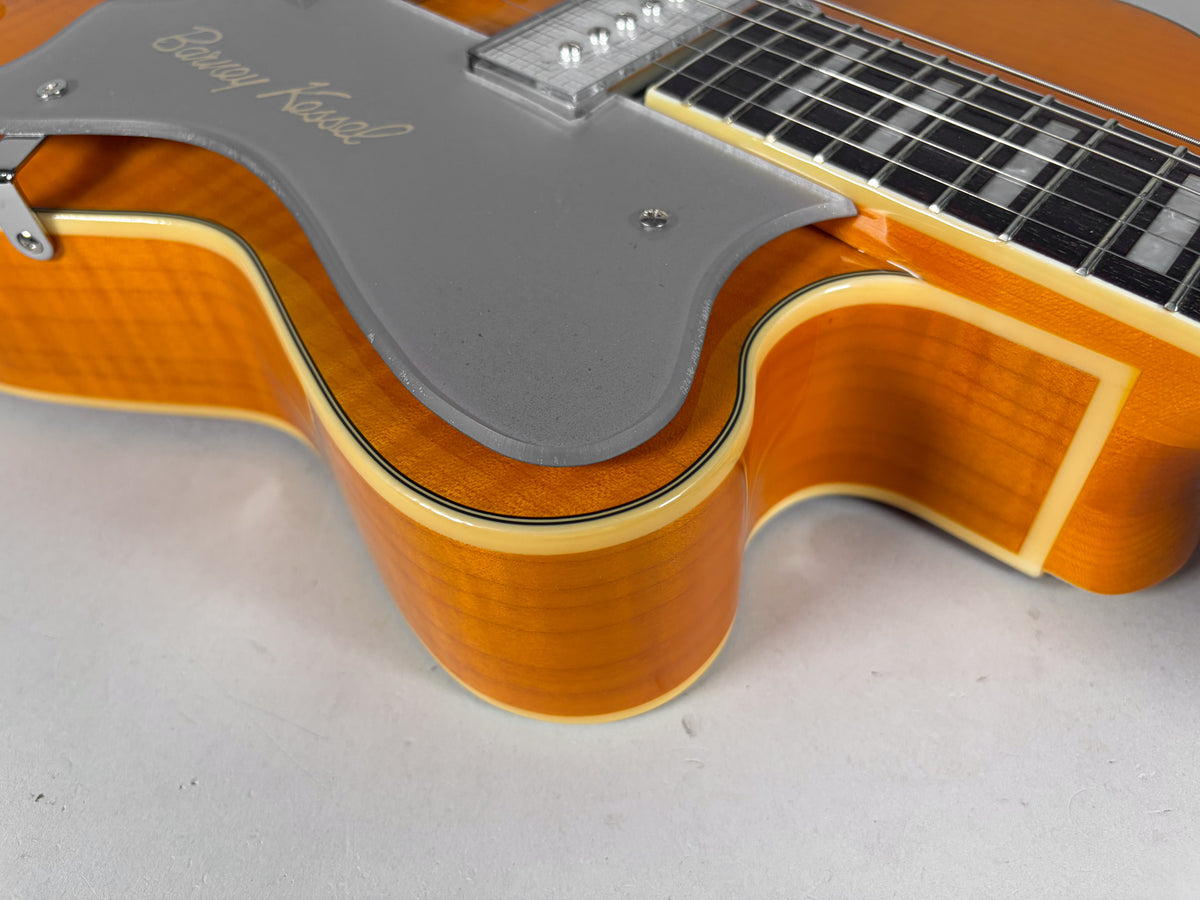 Close-up of the guitar's amber body, showing the light grey pickguard with "Barney Kessel" script and multi-ply binding.