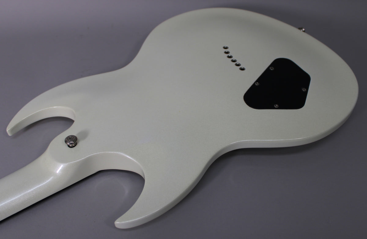 The back of a white double-cutaway electric guitar with a glitter finish, showing string-through-body ferrules and a black control cavity cover.