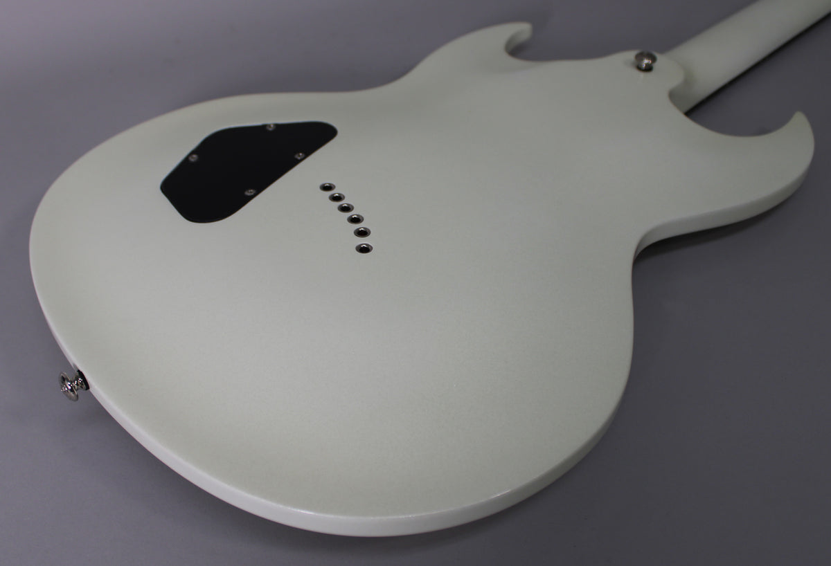 The back of a white electric guitar with a subtle sparkle finish, showing a black control cavity cover and six string-through-body ferrules.