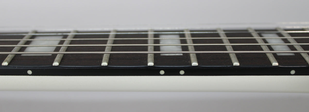 Close-up of the guitar's dark fretboard with rectangular white inlays, showing frets and strings, and white side dots.