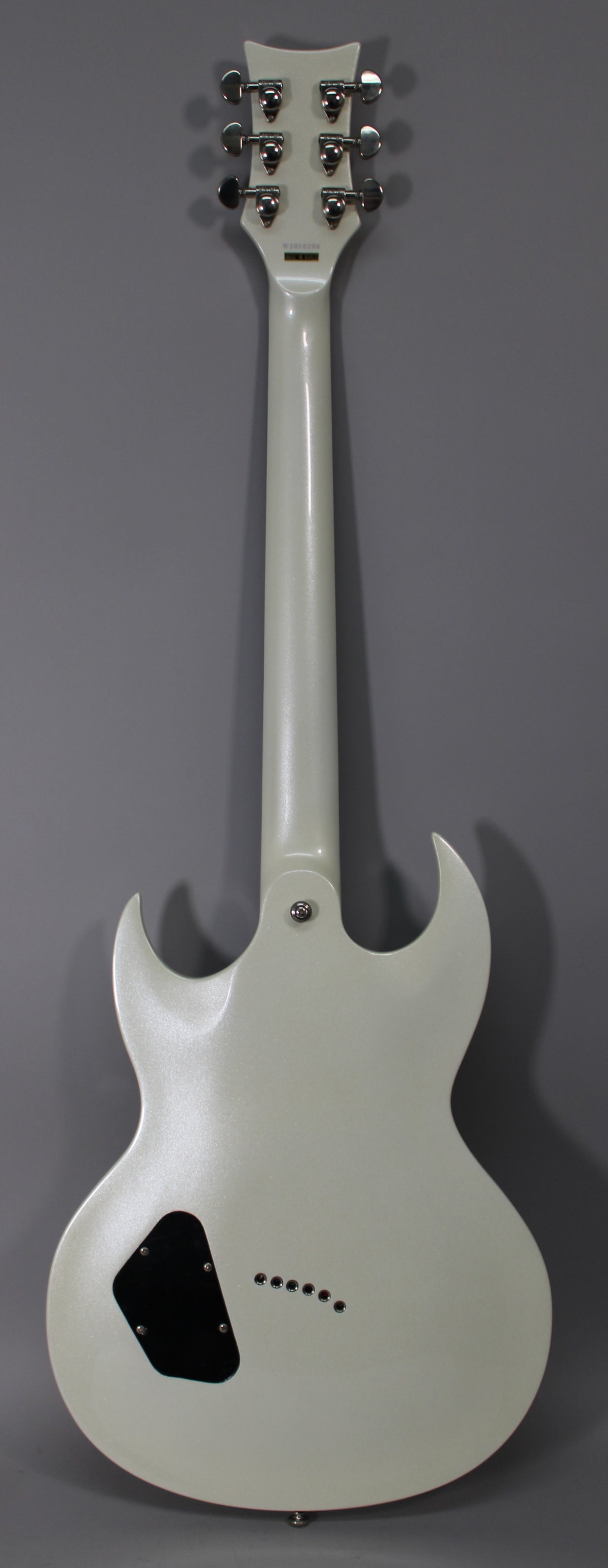 Full rear view of a white electric guitar with a pearlescent finish, chrome tuners, and a black control cavity cover.