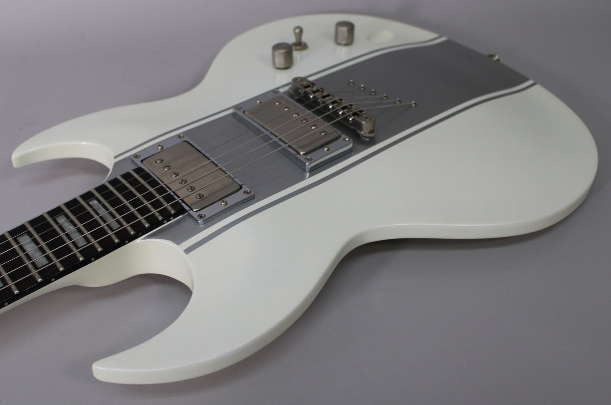 The white electric guitar's body, with a wide silver stripe and thin silver outlines, is angled from the neck to the lower bout.